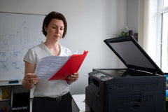 Woman reviewing documents beside office printer