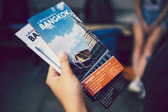 Person holding a Bangkok travel guide booklet